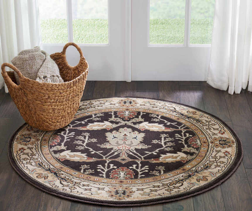Entryway with a round Nourison Walden Bistre rug, dark wood floors, white door, and a basket of blankets.
