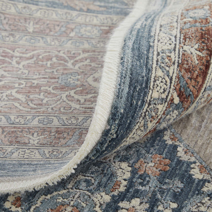 Close up of the Feizy Marquette Gray/Red/Blue Area Rug showing the medallion pattern, fringe, and texture. Fold