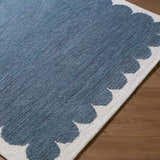 Close up of the blue and ivory Lukamu Modern Art Deco Rug with a scalloped edge detail. Corner