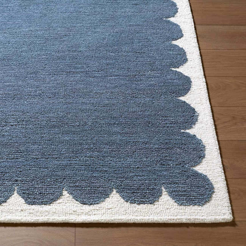 Close-up of the Lukamu rug, a blue wool rug with a scalloped ivory border, hand-tufted for a textured, contemporary look. Front