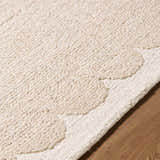 Close up of the beige Lytufa Modern Art Deco rug showing its wool texture and cream scalloped edge. Texture