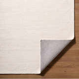 Close up of the hand tufted Kazuto Area Rug in cream wool showing texture and backing. Fold