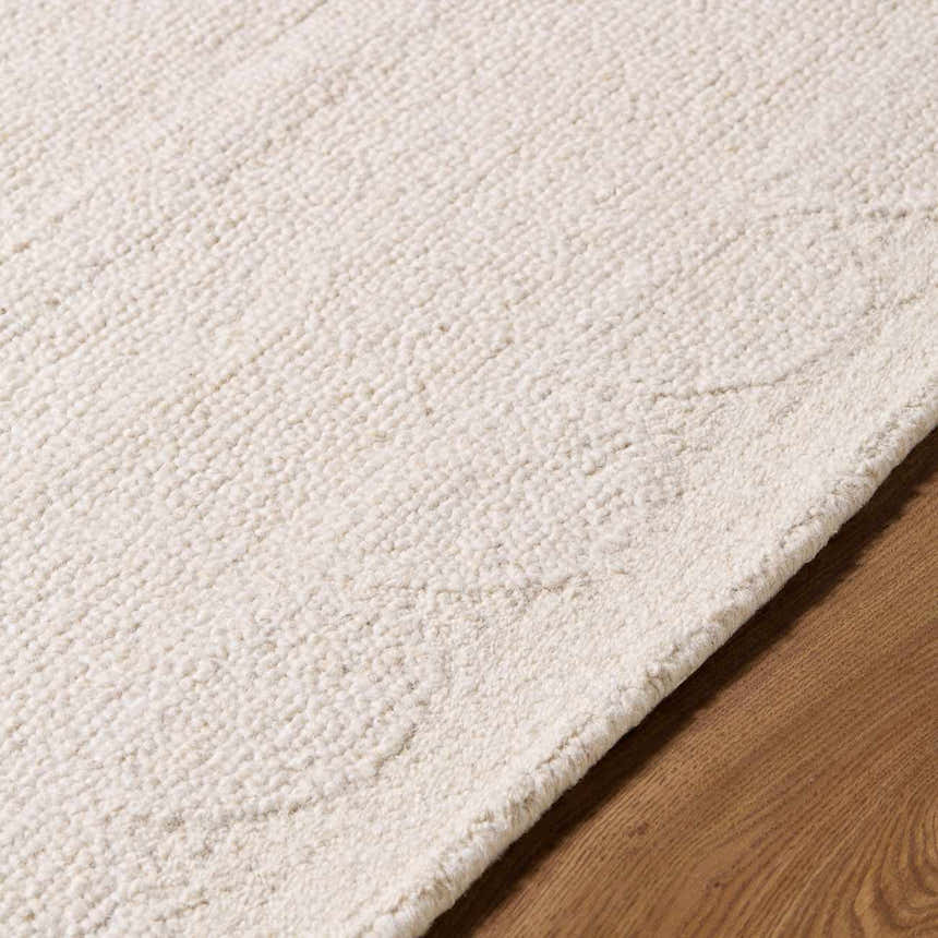 Close-up of the hand-tufted Kazuto Area Rug. Cream and ivory wool texture with subtle pattern detail. Texture