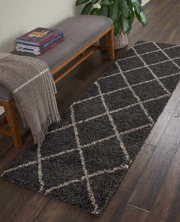 Entryway scene with Nourison Brisbane Charcoal Shag rug runner, gray bench, throw blanket, and dark wood floors.