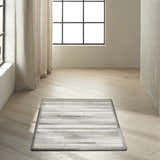 Minimalist room with a Calvin Klein Home Prairie Silver rug on wood floors.