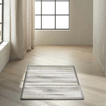 Minimalist room with a Calvin Klein Home Prairie Silver rug on wood floors.