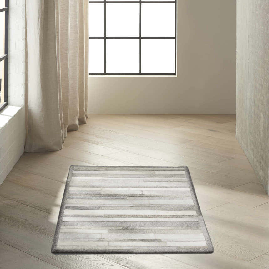 Minimalist room with a Calvin Klein Home Prairie Silver rug on wood floors.