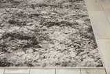 Close-up of the ash-colored Michael Amini Gleam area rug with a textured, abstract pattern on light wood floors.