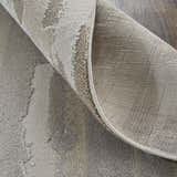 Close-up of the Feizy Vancouver rug showing its abstract ivory, tan, and brown pattern and machine-made construction. Fold