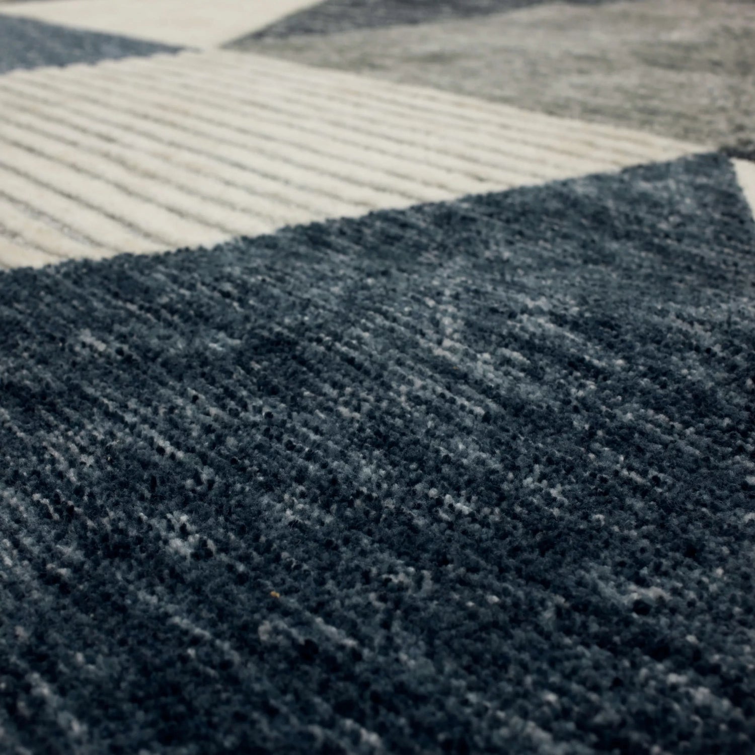 Close-up of the Karastan Oblique Blue Area Rug showing charcoal, cream, denim, and gray colors and contemporary design. Texture