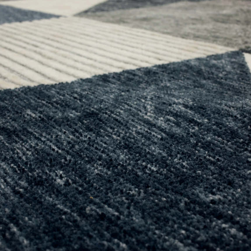 Close-up of the Karastan Oblique Blue Area Rug showing charcoal, cream, denim, and gray colors and contemporary design. Texture