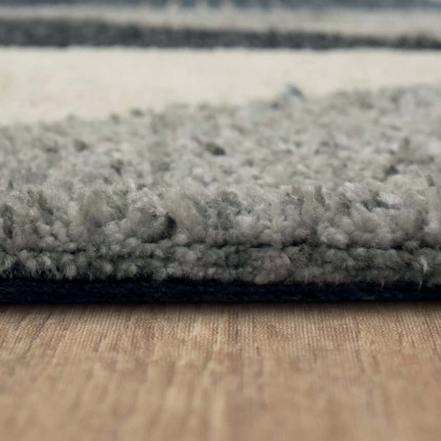 Close-up of the Karastan Oblique Blue Area Rug showing its charcoal, cream, and denim colors and plush texture. Pile
