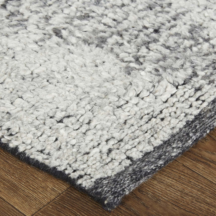 Close-up of the Feizy Alford rug; ivory, gray, and taupe wool with a geometric design and textured, hand-knotted pile. Corner