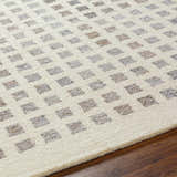 Close-up of the Harib Area Rug. Hand-tufted wool rug with a geometric square pattern in beige, bone, and gray tones. Texture
