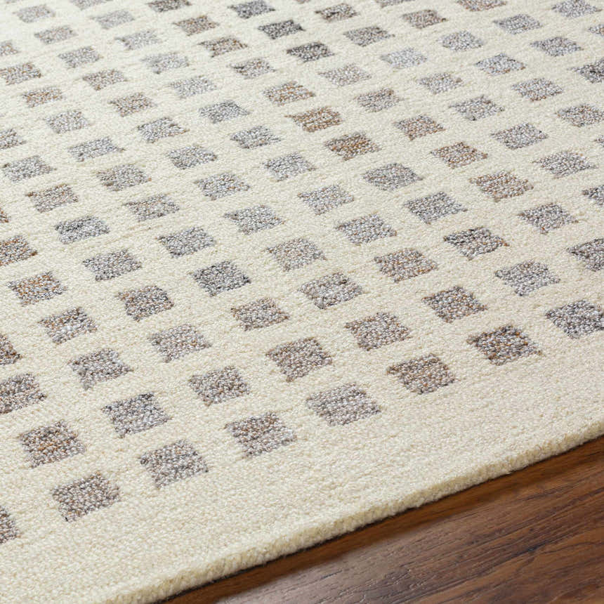 Close-up of the Harib Area Rug. Hand-tufted wool rug with a geometric square pattern in beige, bone, and gray tones. Texture