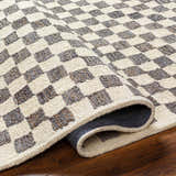 Close-up of the Halen Taupe Checkered Area Rug. Taupe and brown checkered pattern with a textured, hand-tufted construction. Fold