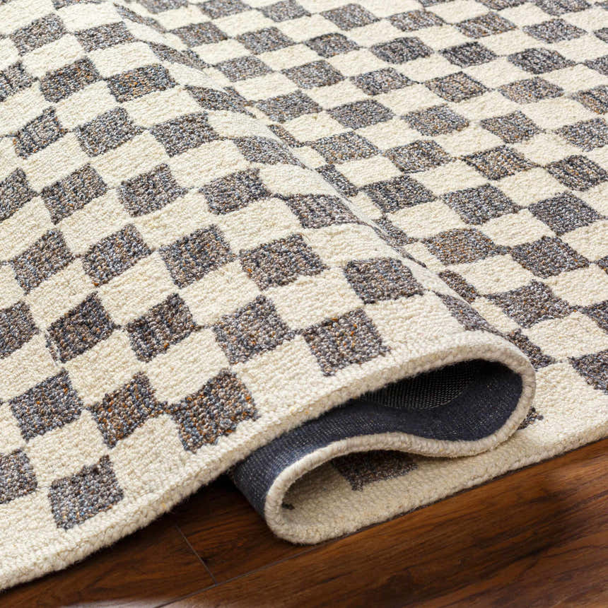 Close-up of the Halen Taupe Checkered Area Rug. Taupe and brown checkered pattern with a textured, hand-tufted construction. Fold
