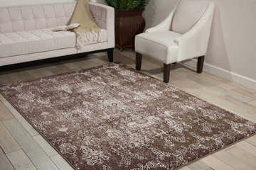 Living room scene with a Nourison Karma Mocha vintage rug, light brown sofa, and white accent chair.