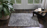 Entryway with Nourison Ellora Slate rug, dark wood floors, potted plant, and patterned ottoman near a bright window.