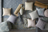 Textured Sherwood Area Rug in ice blue with pillows, pouf, and rolled rugs on a wood floor. Styleshot
