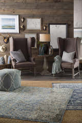 Rustic living room scene with a blue Sherwood Area Rug, brown wingback chairs, and wood paneled walls. Roomscene-Rectangle