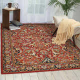 Living room scene with a Nourison Timeless Red Traditional rug, chair with throw, side table, and light wood floors.