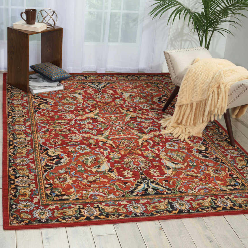 Living room scene with a Nourison Timeless Red Traditional rug, chair with throw, side table, and light wood floors.