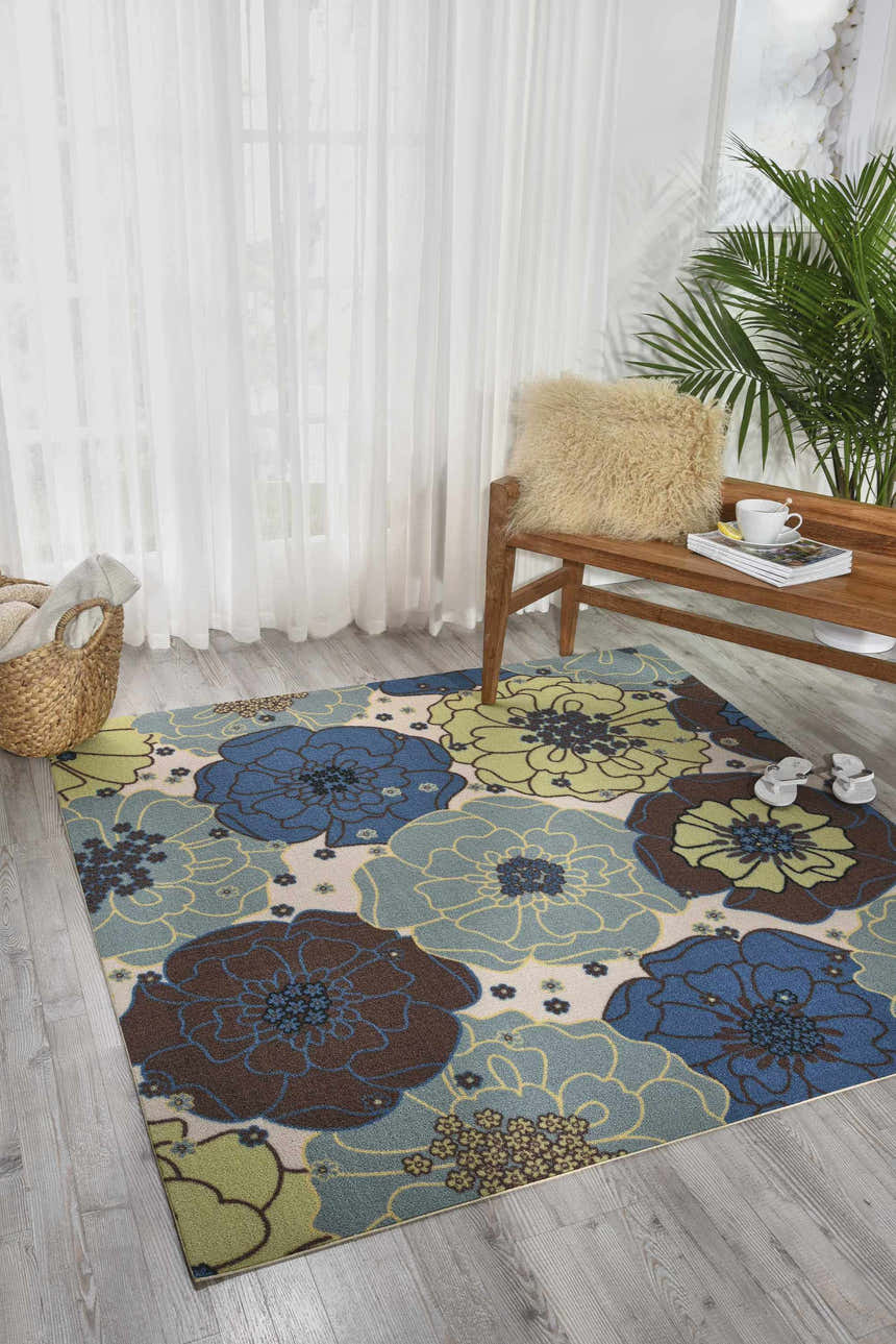 Sunlit room scene with a Nourison Home & Garden Light Blue rug featuring a large floral pattern in blue, brown, and green.