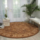 Sunlit room scene with a round Nourison 3000 Taupe Persian rug, white bench, and plants. Airy and bright decor.