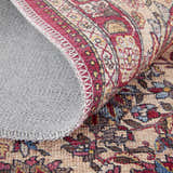 Close up of Feizy Rawlins rug shows red, tan, and pink floral pattern and gray cotton backing. Transitional oriental style. Fold