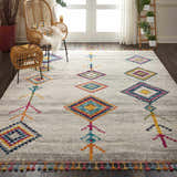 Living room with rattan furniture and Nourison Nomad cream grey tribal rug with colorful diamond pattern.