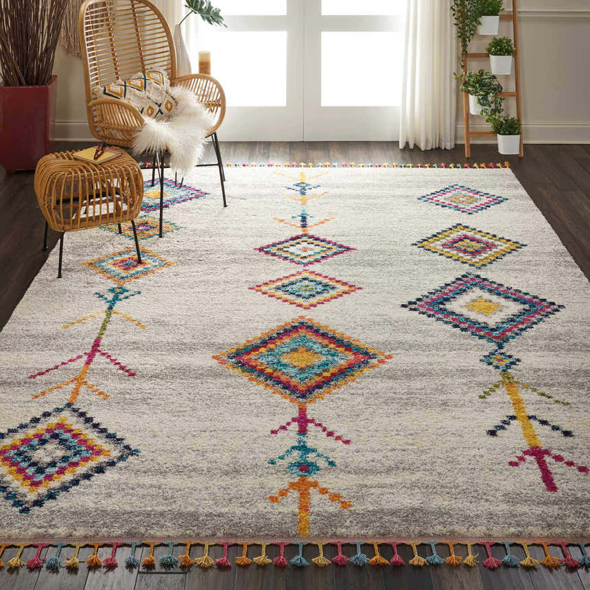 Living room with rattan furniture and Nourison Nomad cream grey tribal rug with colorful diamond pattern.