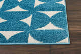 Close-up of Nourison Harper Blue Colorful rug with geometric white pattern on dark wood floor.