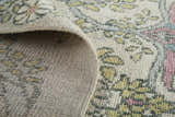 Close-up of the Feizy Beall rug showing its hand-knotted wool texture and ivory, pink, and green floral design. Fold