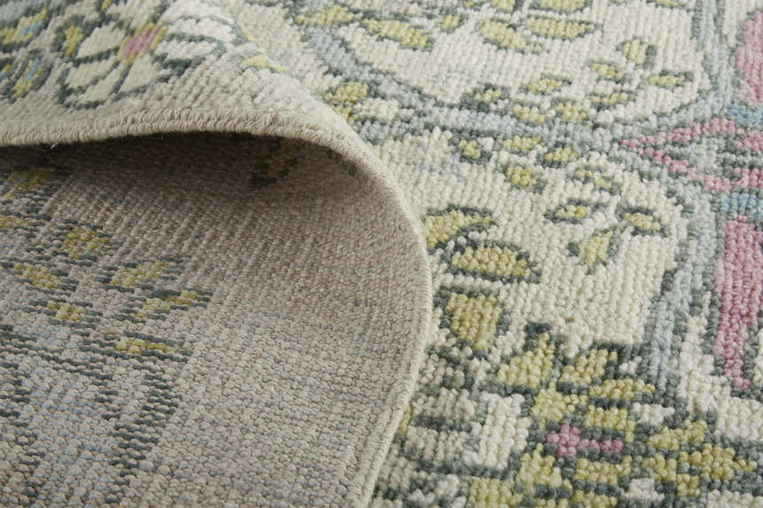 Close-up of the Feizy Beall rug showing its hand-knotted wool texture and ivory, pink, and green floral design. Fold