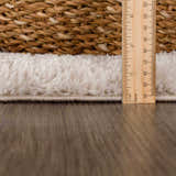 Close-up of the Velora Light Beige rug showing its shag texture, pile height with a ruler, and woven edge. Pile