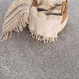 Close-up of the gray Lunaro rug texture with a basket, pillow, and throw blanket. Modern, minimalist style. Swatch