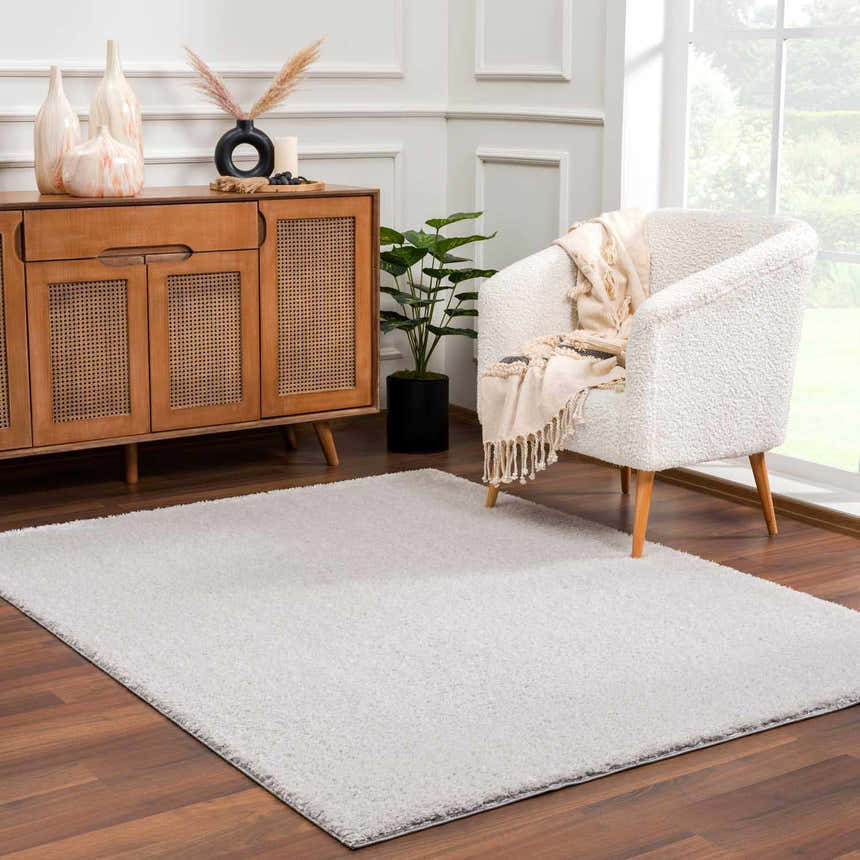 Living room scene with a Lunaro Gray wavy abstract rug, wood cabinet, and white chair. Roomscene-Rectangle