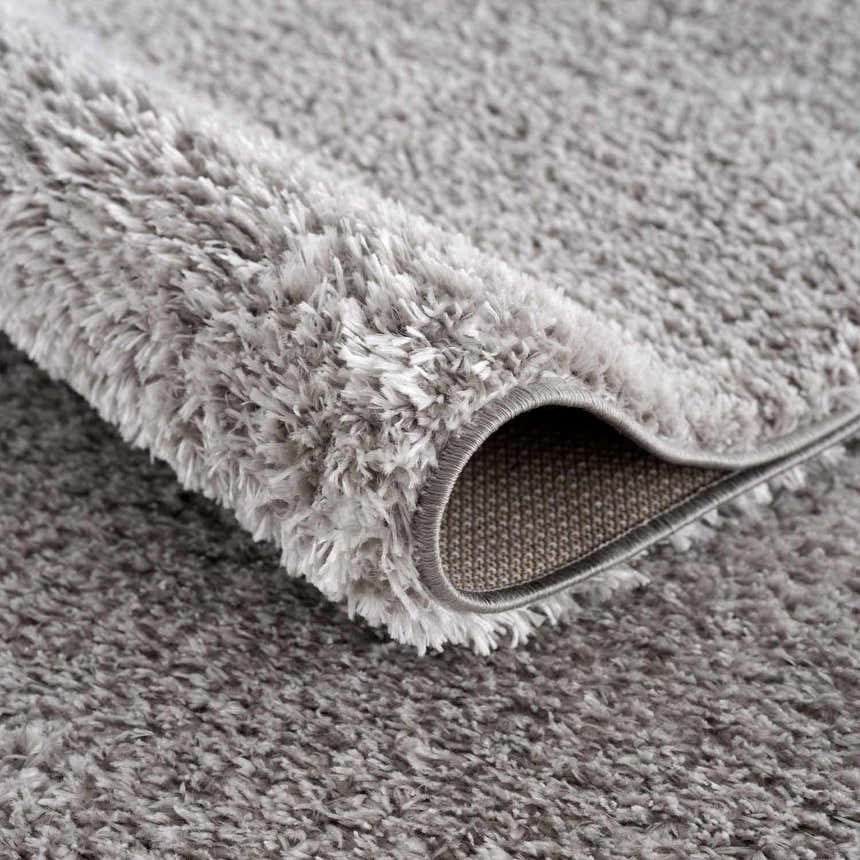 Close-up of the plush, gray Lunaro shag rug. Soft polyester fibers create a subtle wavy texture. Fold