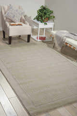 Living room scene with a Nourison Westport Grey rug, armchair, white table, and bench.