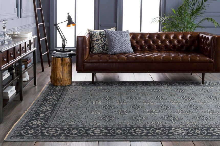 Living room scene with a brown leather sofa and a blue Sherwood Area Rug with a traditional pattern. Roomscene-Rectangle