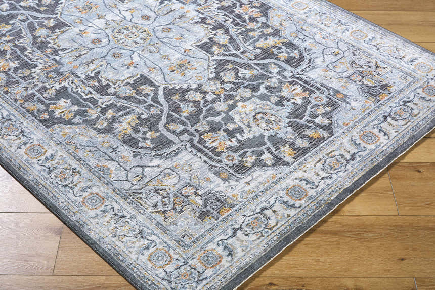 Close-up of the Hayfa Area Rug, a traditional design in dark gray, light gray, and gold tones on a wood floor. Corner