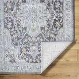 Close-up of the Hayfa Area Rug. Dark gray, light gray, and blue traditional floral pattern. Machine woven texture. Fold