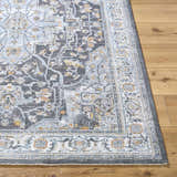 Close-up of the gray Hayfa Area Rug on wood flooring, showcasing its traditional floral pattern and soft texture. Front