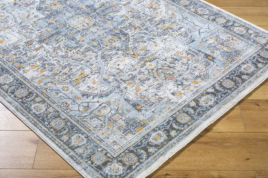 Close-up of the Hovan Area Rug showing its cloud gray, light blue, and gold traditional pattern and dark gray border. Corner