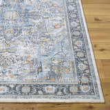 Close-up of the Hovan Area Rug, a traditional style rug in cloud gray, light blue, and gold on a wood floor. Front