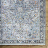 Close-up of the Hovan Area Rug: gray, light blue, and orange traditional pattern on a wood floor. Corner