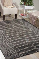 Living room scene with a taupe Nourison Maxell Charcoal rug, white chair, and wood floors.