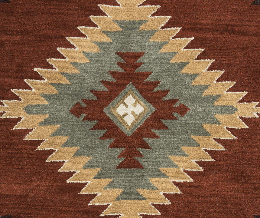 Close-up of the Rizzy SU1822 area rug showing a Southwestern diamond pattern in navy, off-white, red, sage, and tan. Texture
