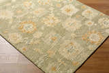 Close-up of the Rihuce Traditional Handmade Area Rug, a wool rug with a floral pattern in sage, cream, and pale yellow. Corner